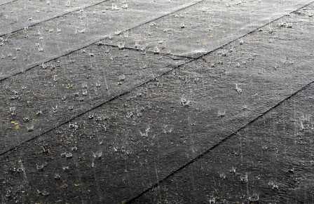 Des gouttes de pluie tombent sur une surface où on voit des carreaux.
