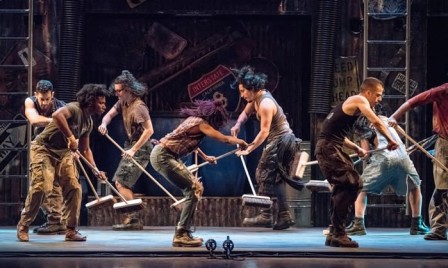 Sur une scène, des personnes semblent passer le balai ; en réalité, elles font de la musique.